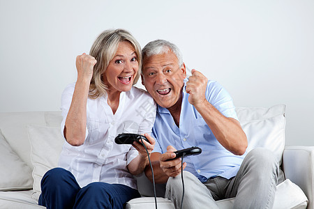 玩电子游戏的情侣女性丈夫微笑游戏乐趣朋友闲暇享受女士养老金背景图片