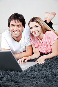 使用笔记本电脑的年轻夫妇地毯男性妻子房子闲暇娱乐技术地面男朋友喜悦图片