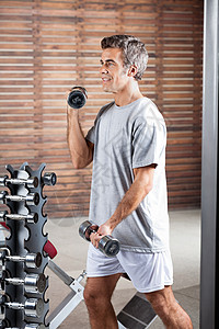 卫生中心的人举起哑铃福利卷曲重量架子运动员训练举重手臂二头肌男性图片