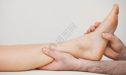 将脚踝按在病人脚踝上的Chiropodist图片