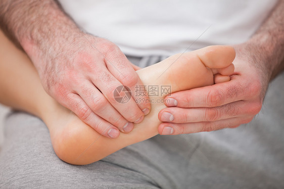 Podiatrist 按摩一个女人的脚 同时将脚放在他身上图片