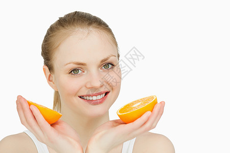 手握橙子的笑女人果味快乐微笑金发女性头发金发女郎配售女士水果背景图片