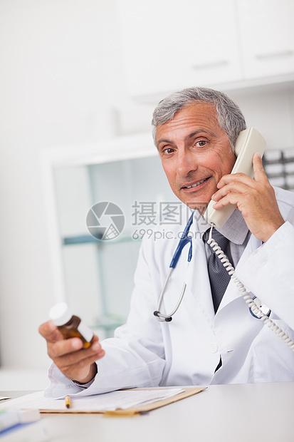 医生坐着时拿着药箱和电话图片
