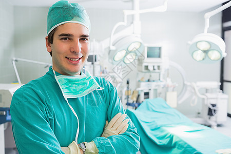 外科医生笑着用手跨过深色微笑手术双臂设备闪电头发磨砂膏手术室男人图片