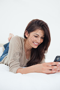 近近一点 女人用她的手机 在床上微笑图片