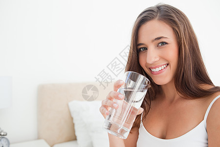 女人微笑着 当她拿着一杯水时图片