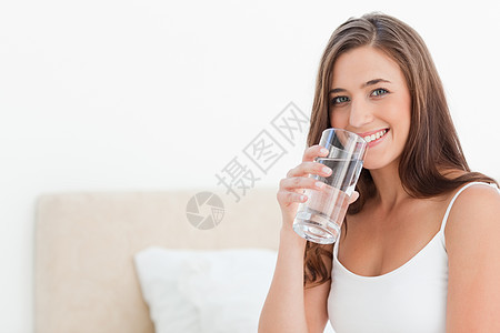 女人用玻璃杯顶着嘴微笑图片