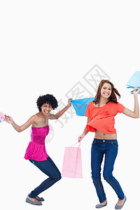 青少年在朋友站立时伸展她的双腿购物衣服喜悦消费者影棚女性快乐友谊开支外表图片