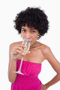 年轻女子喝杯香槟 对抗白灰色的背面图片