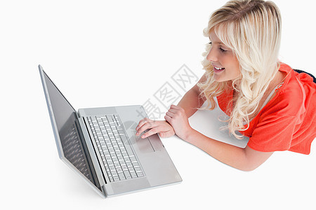 微笑的女人躺着看着她的笔记本电脑图片