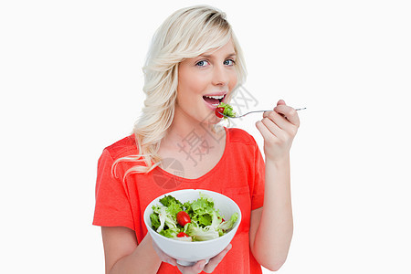 被一个微笑着的美发女人吃掉的蔬菜沙拉图片