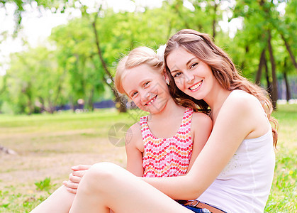母亲和女儿一起坐在草地上花园场地乐趣家庭生活地面女孩成人婴儿孩子图片