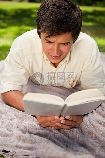 男人躺在毯子上 却在读书图片