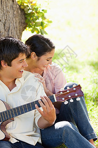 女人与玩吉他的朋友一起欢笑图片