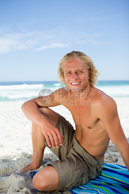 笑脸男人坐在沙滩毛巾上看着摄像机 看镜头图片