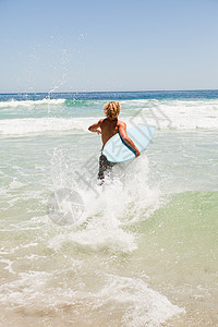 金发人拿着冲浪板在水中奔速跑来跑去背景图片