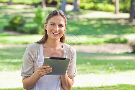 带着平板电脑在公园里微笑的女人图片