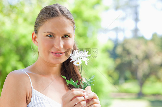 女人在公园里拿着花朵图片