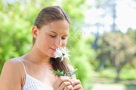 女人在公园一朵花上闻着香味图片