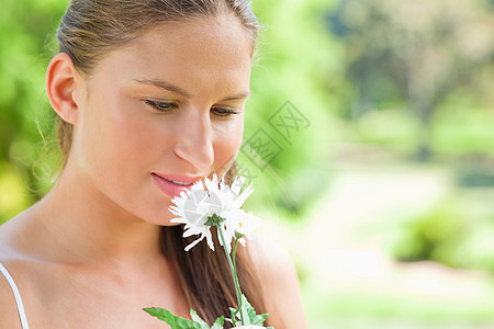女人在公园一朵白花上闻着香味图片