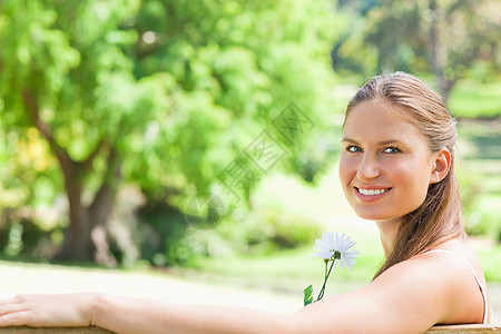 一个带着花朵微笑的女人的侧面景色图片