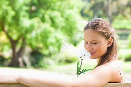 女人的侧边景色闻着一朵花的香味图片