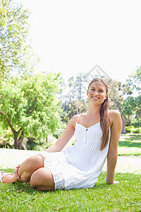 坐在草坪上的公园里微笑的女人图片