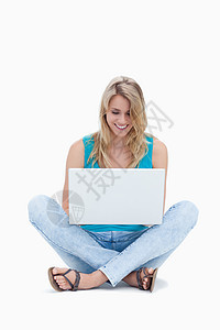 一个女人坐在地上看着她的笔记本电脑图片