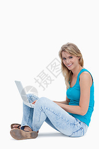 一个女人对着摄像机微笑 腿上有笔记本电脑图片