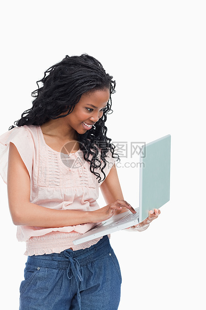 一个快乐的年轻女人 正在她手上的笔记本电脑上打字图片