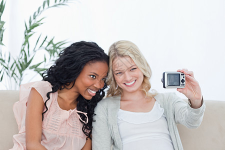一个女人用数码摄像头拍摄自己和朋友的照片图片
