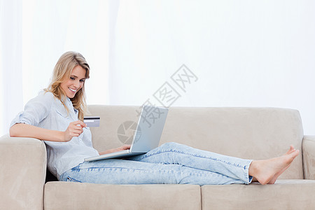 一个女人躺在沙发上 笔记本电脑在她面前图片