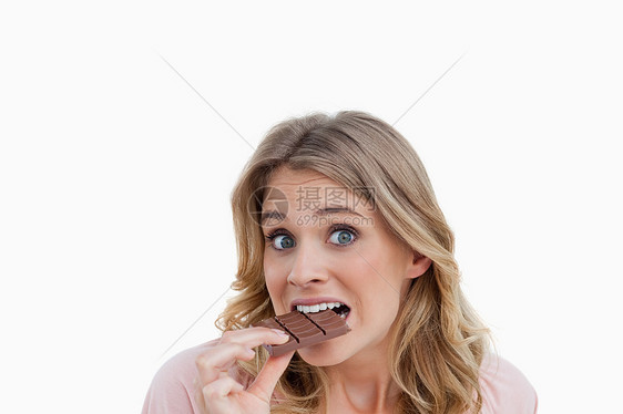 年轻金发金发美女在吃巧克力时看镜头图片