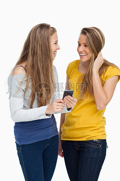 两名女学生在拿着手机时笑着笑图片