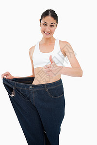微笑的女人 谁失去了很多体重的重量 拇指成就长度影棚裤子外表身体牛仔裤腹部尺寸饮食图片