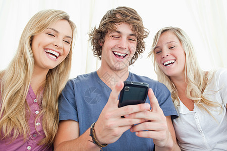 三个朋友一边看着手机屏幕边 一边笑着看图片