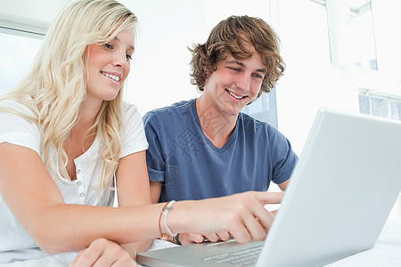 一对笑着的夫妇在用笔记本电脑指着屏幕时图片