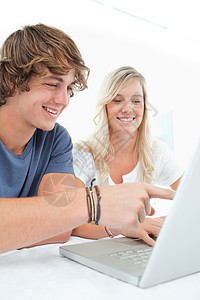 一对微笑的情侣看着笔记本电脑时图片
