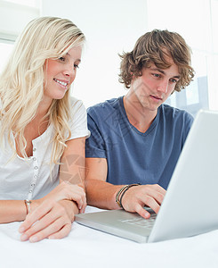 一对微笑的夫妇坐着使用笔记本电脑图片