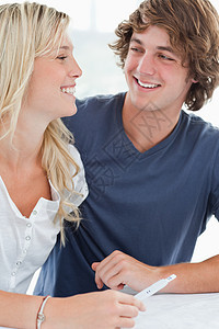一个微笑的一对夫妇在彼此怀孕时互相看着对方图片