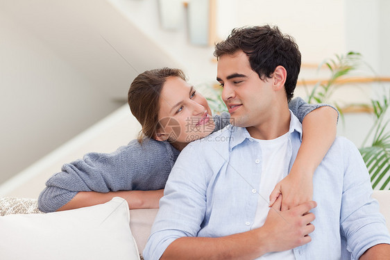 年轻夫妇抱抱亲热年轻人沙发感情微笑长椅房间夫妻闲暇妻子图片