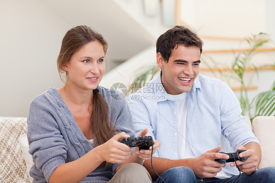 玩电子游戏的年轻夫妇竞赛控制朋友们闲暇沙发丈夫年轻人安慰专注活动图片