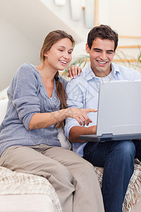 一对夫妇使用笔记本电脑的肖像女性互联网妻子快乐微笑沙发拥抱年轻人网络沟通图片