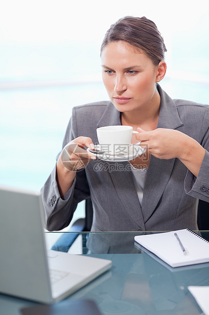 一位严肃的女商务人士喝茶的肖像图片