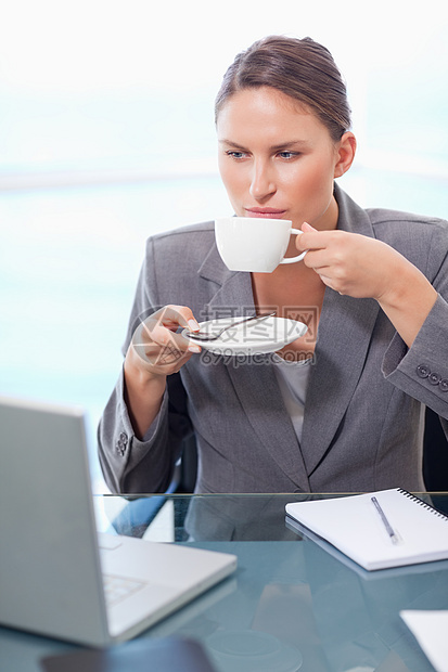 一位严肃的女商务人士喝咖啡的肖像图片