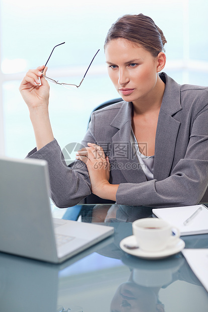 使用笔记本电脑的女商务人士肖像职业咖啡饮料女性商业杯子桌子技术眼镜商务图片