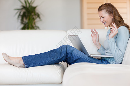 带着笔记本电脑在沙发上微笑的快乐女人图片