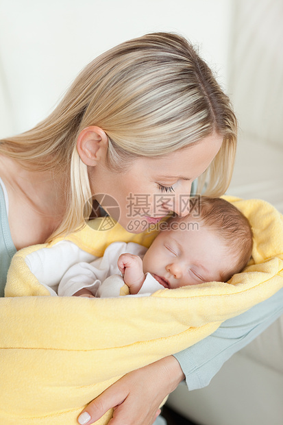柔情的母亲亲吻她怀中睡着的婴儿图片