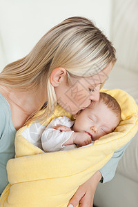 感动的母亲亲吻她新生儿的前额图片