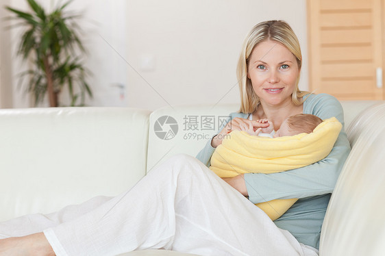 母亲坐在沙发上 抱着婴儿在她的怀里图片